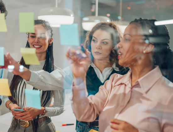 People sticking notes to a clear surface
