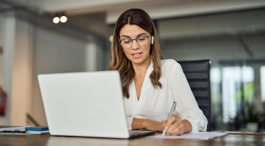 Woman taking notes while at a laptop