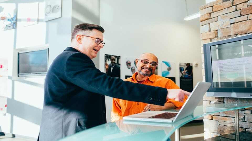 man-in-suit-talking-to-man-in-orange-shirt